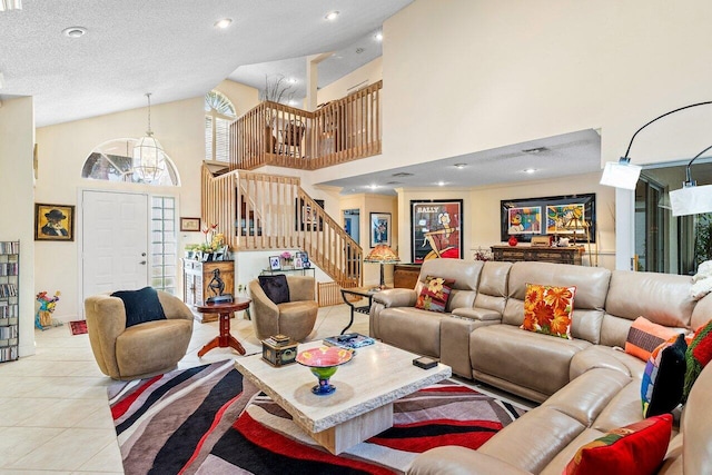 living room with a notable chandelier, a textured ceiling, light tile patterned flooring, and a high ceiling