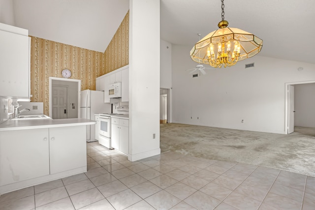 kitchen with white cabinets, white appliances, sink, decorative light fixtures, and light colored carpet