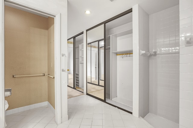 bathroom with tile patterned flooring, tiled shower, and toilet