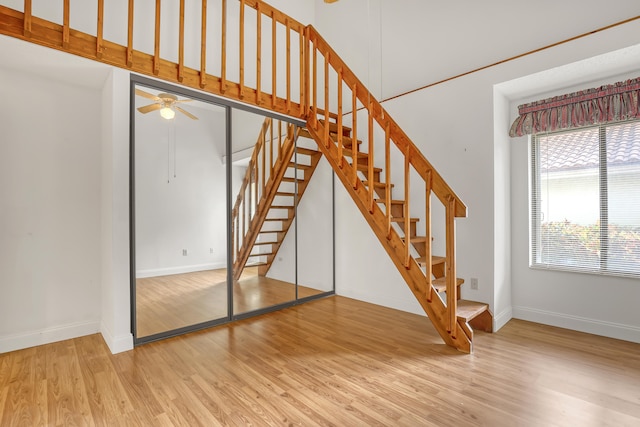 stairs with ceiling fan and hardwood / wood-style flooring