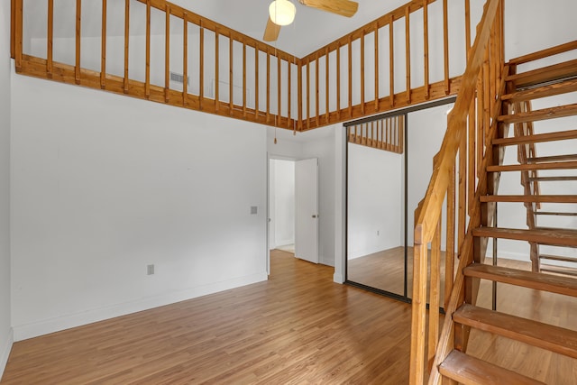 staircase featuring a high ceiling, hardwood / wood-style flooring, and ceiling fan