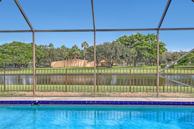 view of pool with a water view, glass enclosure, and a lawn