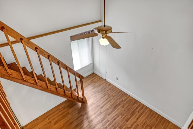 staircase featuring ceiling fan, beam ceiling, and hardwood / wood-style floors