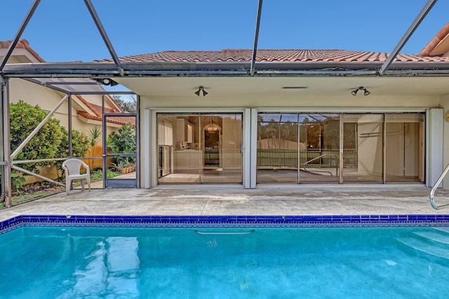 back of property with glass enclosure and a patio