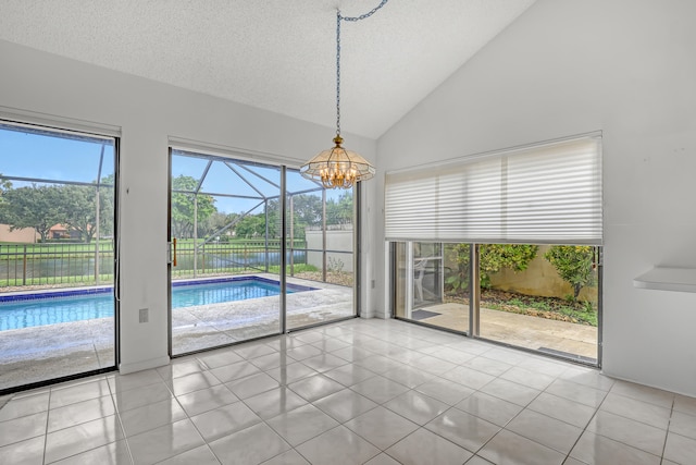 unfurnished dining area featuring lofted ceiling, a chandelier, light tile patterned floors, and a textured ceiling