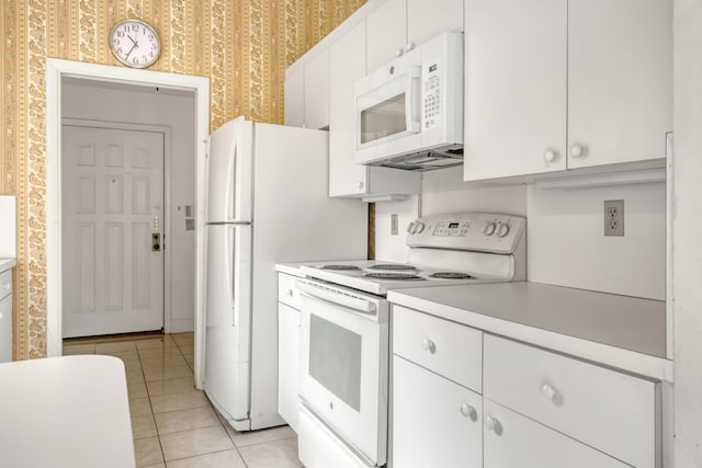 kitchen featuring light tile patterned floors, white appliances, and white cabinetry