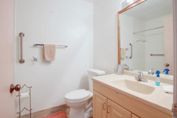 bathroom featuring a shower, tile patterned flooring, vanity, and toilet