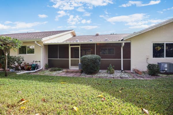 rear view of house featuring a sunroom and a lawn