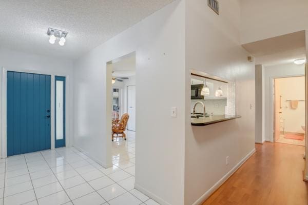 tiled entryway with ceiling fan, sink, and a textured ceiling