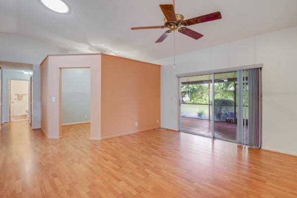 unfurnished room with ceiling fan, light wood-type flooring, and vaulted ceiling