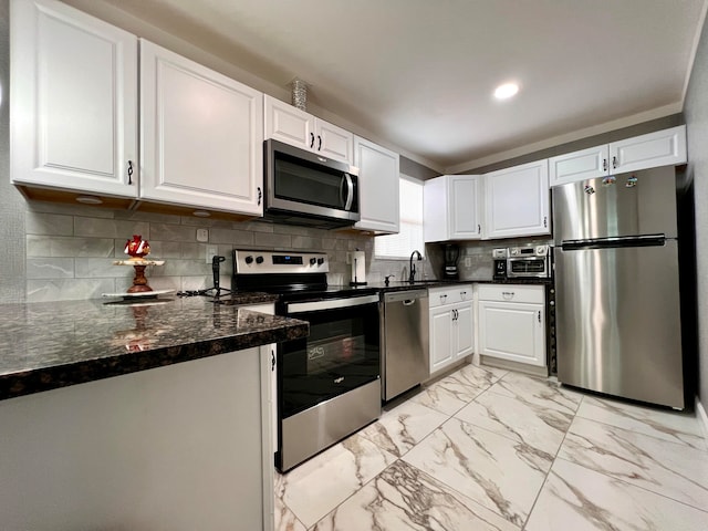 kitchen with sink, white cabinetry, stainless steel appliances, dark stone counters, and decorative backsplash