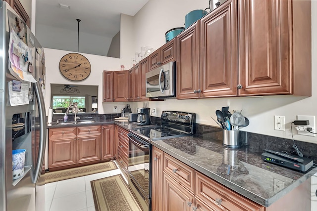 kitchen with lofted ceiling, sink, light tile patterned flooring, dark stone counters, and appliances with stainless steel finishes