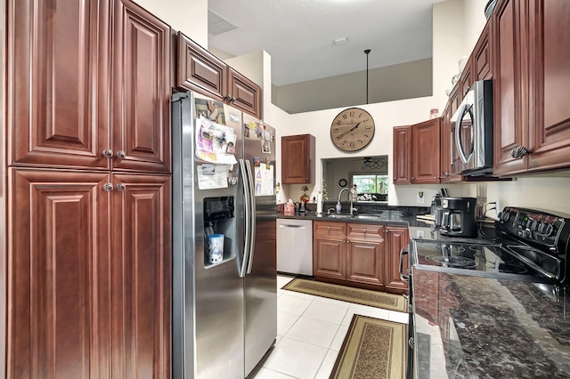 kitchen featuring stainless steel appliances, dark stone countertops, sink, and light tile patterned floors