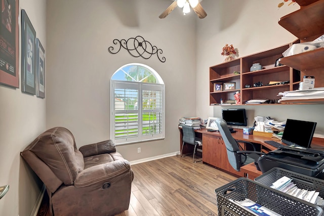 office space featuring a high ceiling, ceiling fan, and wood-type flooring