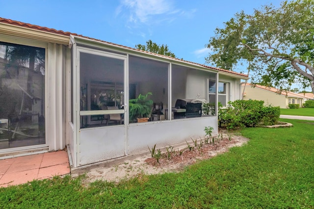 view of side of property with a yard and a sunroom