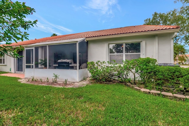 back of house with a yard and a sunroom