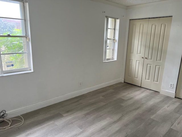 unfurnished bedroom with a closet, light hardwood / wood-style flooring, and multiple windows