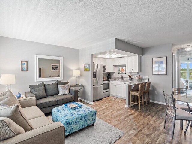 kitchen featuring white cabinets, sink, appliances with stainless steel finishes, a kitchen breakfast bar, and a textured ceiling