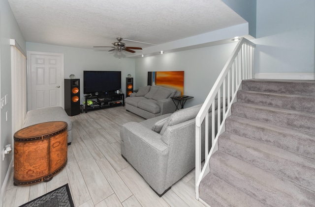 living room with ceiling fan, light hardwood / wood-style floors, and a textured ceiling