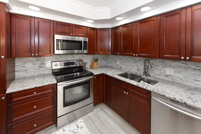 kitchen featuring light stone countertops, tasteful backsplash, sink, ornamental molding, and appliances with stainless steel finishes