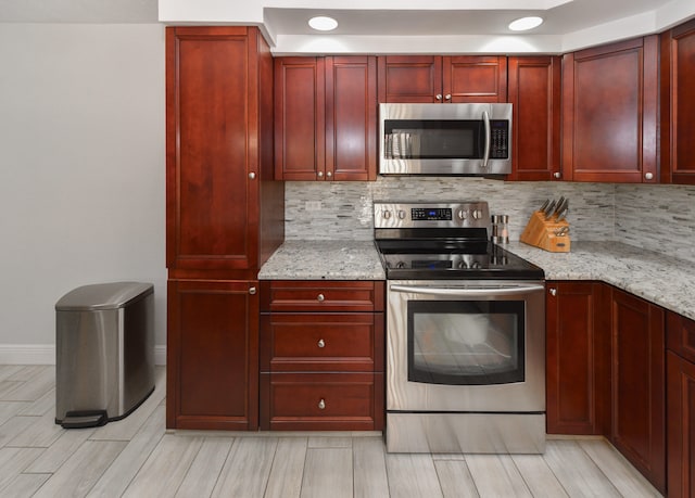 kitchen featuring light stone countertops, stainless steel appliances, light wood-type flooring, and tasteful backsplash