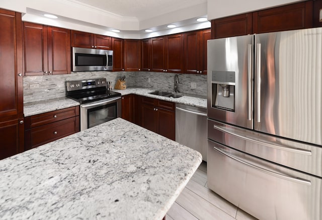 kitchen with light stone counters, appliances with stainless steel finishes, sink, and decorative backsplash