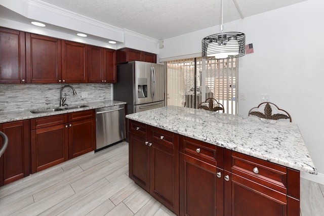 kitchen featuring sink, a textured ceiling, appliances with stainless steel finishes, light stone countertops, and crown molding