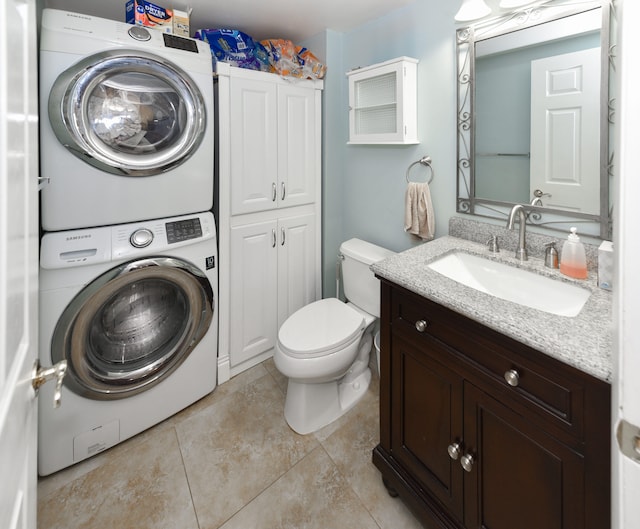 bathroom featuring stacked washer and clothes dryer, tile patterned flooring, toilet, and vanity