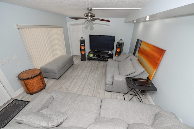 living room with ceiling fan, a textured ceiling, light hardwood / wood-style flooring, and lofted ceiling