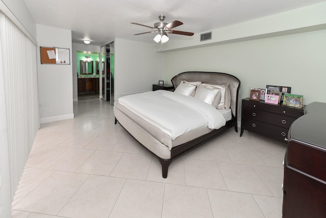 bedroom with a textured ceiling, ceiling fan, light tile patterned floors, and ensuite bath