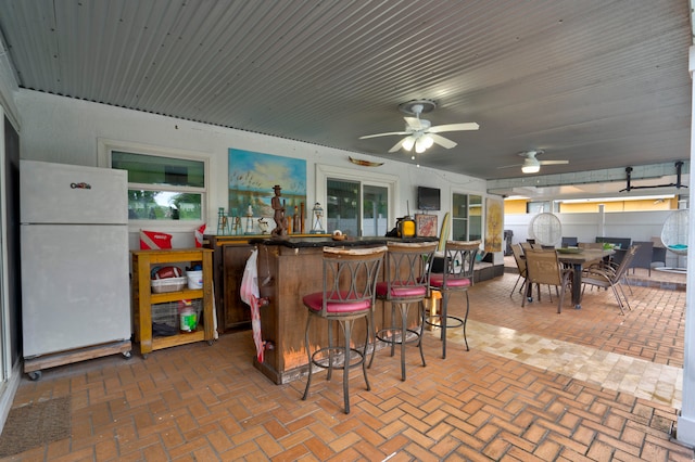 kitchen with ceiling fan, white refrigerator, and a kitchen breakfast bar