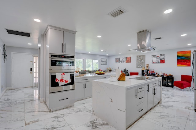 kitchen featuring a center island, light stone countertops, double oven, island range hood, and black electric stovetop