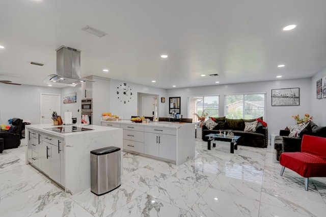 kitchen with a kitchen island, stainless steel double oven, island exhaust hood, and white cabinetry