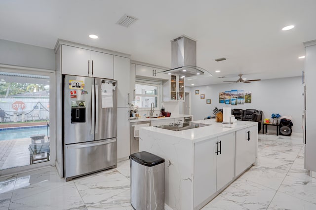 kitchen with appliances with stainless steel finishes, island exhaust hood, plenty of natural light, and white cabinetry