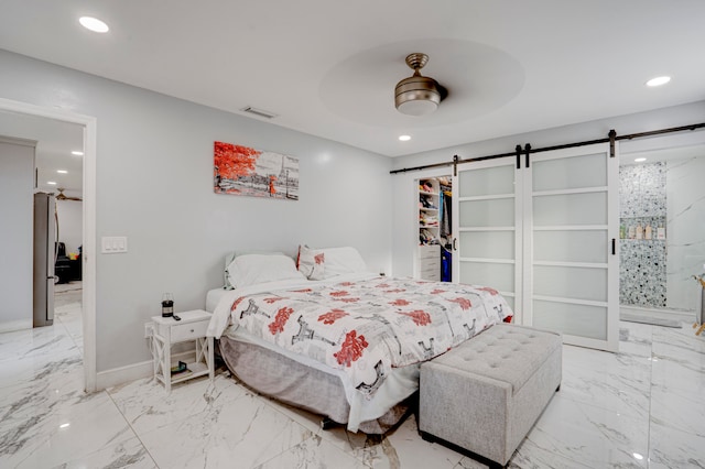 bedroom featuring ceiling fan, a closet, a barn door, and a walk in closet