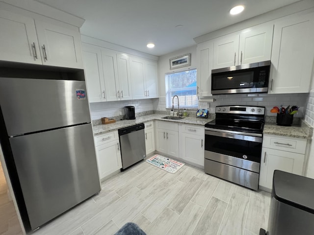 kitchen featuring sink, decorative backsplash, white cabinets, and appliances with stainless steel finishes