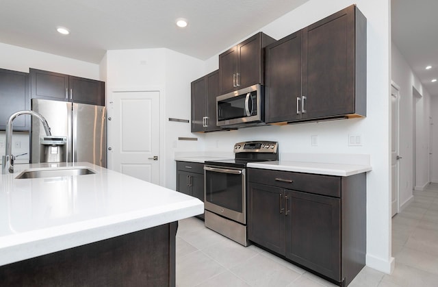 kitchen featuring dark brown cabinets, light tile patterned flooring, appliances with stainless steel finishes, and sink