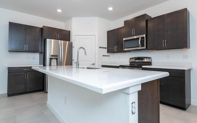 kitchen with dark brown cabinets, a kitchen island with sink, and stainless steel appliances