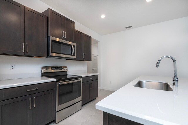 kitchen featuring light tile patterned flooring, appliances with stainless steel finishes, sink, and dark brown cabinets