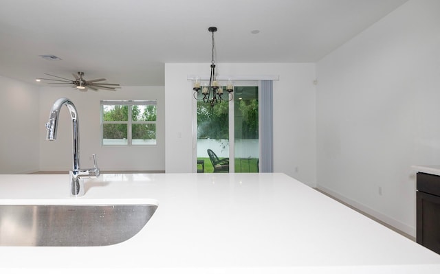 kitchen with ceiling fan with notable chandelier, hanging light fixtures, and sink