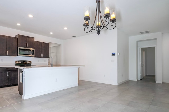 kitchen with dark brown cabinets, decorative light fixtures, a center island with sink, and appliances with stainless steel finishes