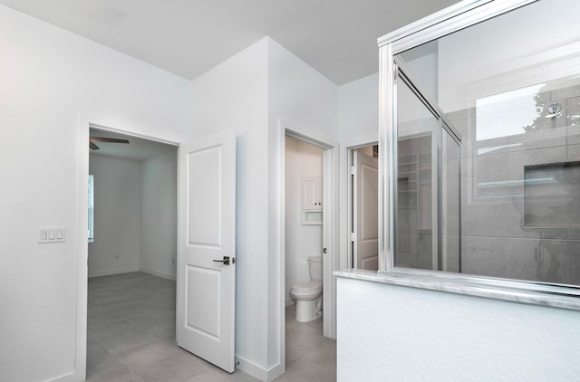 bathroom featuring ceiling fan, toilet, an enclosed shower, and tile patterned floors