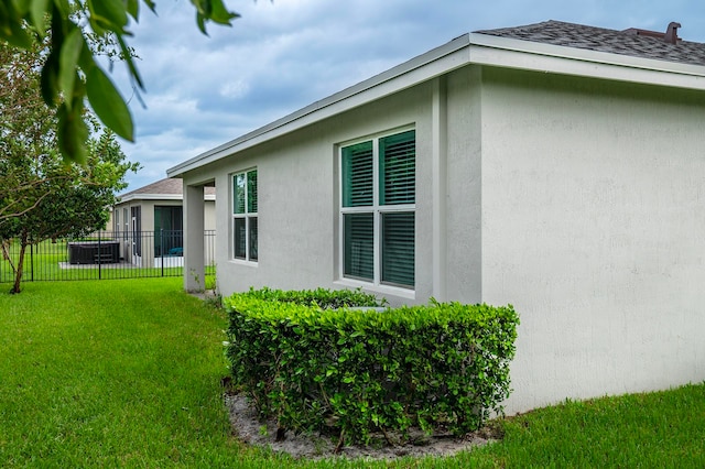 view of side of home with central AC unit and a lawn