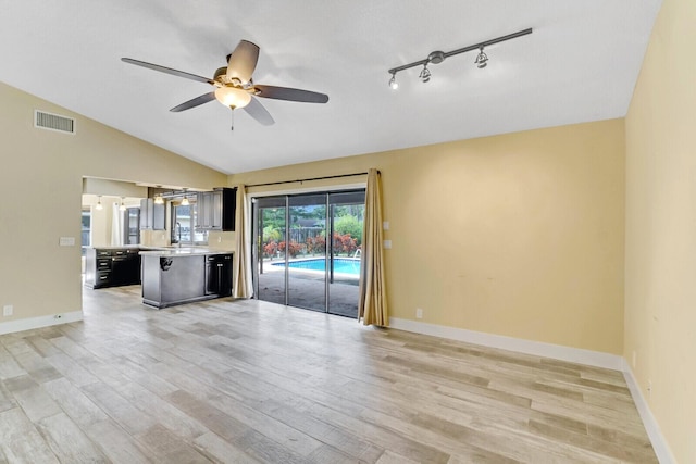 unfurnished living room with light hardwood / wood-style floors, vaulted ceiling, ceiling fan, and sink