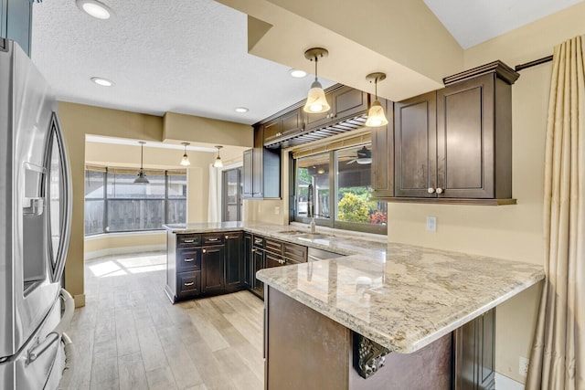 kitchen with decorative light fixtures, stainless steel fridge, and kitchen peninsula