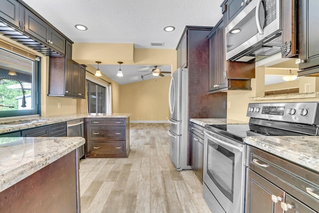 kitchen with appliances with stainless steel finishes, light wood-type flooring, light stone counters, ceiling fan, and decorative light fixtures