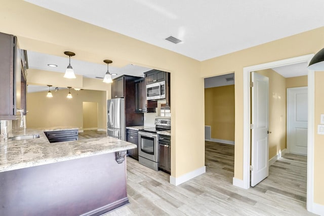 kitchen featuring kitchen peninsula, stainless steel appliances, light stone counters, and light hardwood / wood-style flooring