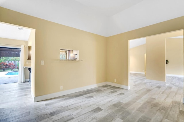 empty room with light hardwood / wood-style flooring and lofted ceiling