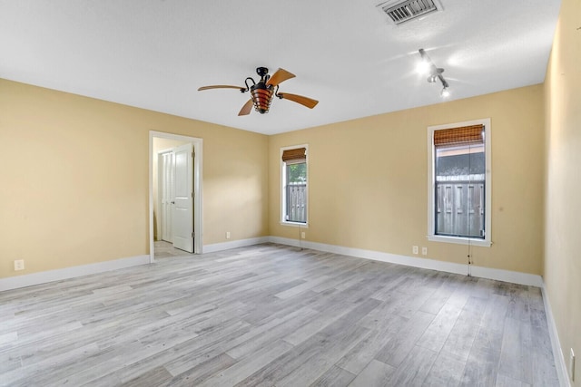 empty room featuring a wealth of natural light, ceiling fan, and light hardwood / wood-style floors