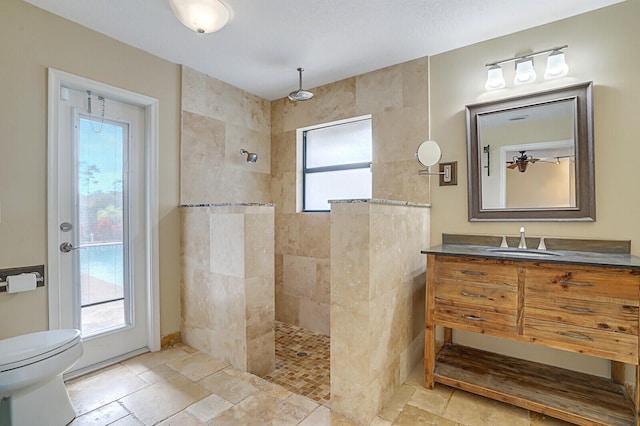 bathroom with tiled shower, vanity, and plenty of natural light